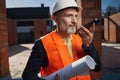 Serious builder in hardhat having a conversation on the phone