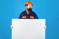 Serious builder man in protective helmet and clothing with advertising banner. Construction Worker in hard hat shows Royalty Free Stock Photo