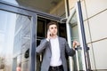 Serious business man in suit talking on phone in office and holding the door Royalty Free Stock Photo