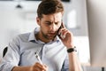 Serious business man talking by smartphone and writing something Royalty Free Stock Photo