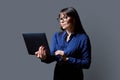 Serious business middle aged woman using laptop on gray background Royalty Free Stock Photo