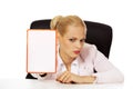 Serious business woman sitting behind the desk and holding board with ban Royalty Free Stock Photo