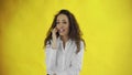 Serious business woman talking mobile phone on yellow background. Portrait of young businesswoman calling phone in Royalty Free Stock Photo