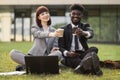 Serious businessman and businesswoman drinking take away coffee sitting on the grass Royalty Free Stock Photo