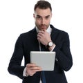 Serious businessman holding tablet and hand on chin while standing Royalty Free Stock Photo