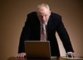 Serious businessman leaning over laptop