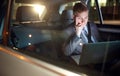Serious businessman in moving car working on his laptop Royalty Free Stock Photo