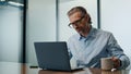 Serious businessman sipping tea in evening workplace closeup. Man typing laptop Royalty Free Stock Photo