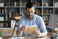 Serious businessman sit at desk holding envelope take out letter