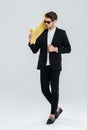 Serious businessman in sunglasses holding yellow skateboard on his sholder