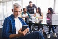 Serious businessman using mobile phone with team working in background Royalty Free Stock Photo