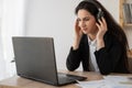 Serious businesswoman in headphones watching webinar on laptop, learning studying computer course, making call Royalty Free Stock Photo