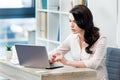 Serious businesswoman sitting at desk and working with laptop in office Royalty Free Stock Photo