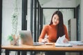 Serious businesswoman using on laptop holding papers preparing report analyzing work results Royalty Free Stock Photo