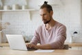 Serious busy freelance worker man typing on laptop in kitchen