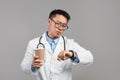 Serious busy middle aged japanese male doctor in white coat and glasses with cup of drink takeaway Royalty Free Stock Photo