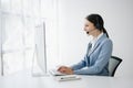 Serious call center operator in wireless headset talking with customer, woman in headphones with microphone consulting client on Royalty Free Stock Photo