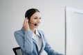 Serious call center operator in wireless headset talking with customer, woman in headphones with microphone consulting client on Royalty Free Stock Photo