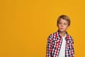 Serious calm blond teenage boy student in shirt looking at empty space