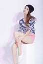 Serious and Calm Caucasian Slim Brunette in Hat Posing On White Box in Studio