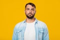 Serious calm mature european man with beard in casual look at camera, isolated on yellow background