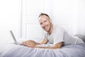 Serious casual young man using laptop in bed at home Royalty Free Stock Photo