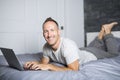 Serious casual young man using laptop in bed at home Royalty Free Stock Photo