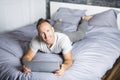 Serious casual young man using laptop in bed at home Royalty Free Stock Photo