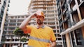 Serious Caucasian builder stands at construction site puts on orange hard hat. Safety first of all, construction profession. Low Royalty Free Stock Photo