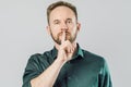Serious caucasian man holding index finger over mouth saying shh Royalty Free Stock Photo