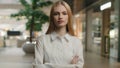 Serious Caucasian woman girl posing in modern office with arms crossed looking at camera. Professional shop assistant Royalty Free Stock Photo