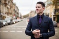 A serious and cheerful businessman in a business suit, adjusting his sleeve and looking to the side, on the streets of the city at Royalty Free Stock Photo