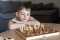 The serious child lost in thought playing chess. Playing board games, on coronavirus quarantine. The child playing chess Royalty Free Stock Photo