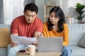Serious chinese couple paying bills online, using laptop Royalty Free Stock Photo