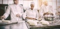 Serious colleagues kneading uncooked dough