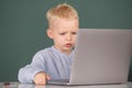 Serious concentrate child using laptop computer, kid boy studying through online e-learning. Little funny system Royalty Free Stock Photo