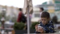 Serious concentrated preoccupied boy playing phone in outdoor cafe Royalty Free Stock Photo