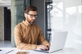 Serious concentrated thinking businessman working inside office with laptop, mature enlightened man in shirt and glasses Royalty Free Stock Photo