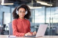 Serious concentrated woman working with laptop inside office, businesswoman thinking with headphones typing on keyboard Royalty Free Stock Photo