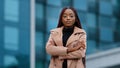 Serious concentrated young african american girl with afro hairstyle standing with folded hands, portrait outdoor Royalty Free Stock Photo