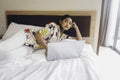 Serious concentrated young woman working from the bed. Hold the laptop on the knees and type on the keyboard