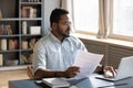 Serious confident African American man using laptop, holding document Royalty Free Stock Photo