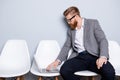 Serious confident bearded business man banker in formal wear typing on his laptop while waiting in the hall on chair Royalty Free Stock Photo