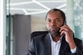 Serious confident businessman close up inside office talking on the phone, african american boss at workplace, company Royalty Free Stock Photo