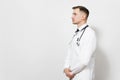 Serious confident experienced handsome young doctor man isolated on white background. Male doctor in medical gown, shirt Royalty Free Stock Photo