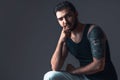 Young man in studio on dark background. Handsome brunette with beard and tattoo in black t-shirt. Portrait Royalty Free Stock Photo