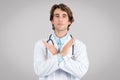 Serious confident man doctor in white coat crossed his arms and making stop gesture, posing on gray background Royalty Free Stock Photo
