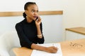 Serious confident young African or black American business woman on phone looking away with notepad in office Royalty Free Stock Photo