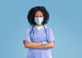 Serious confident young black woman doctor, nurse in blue uniform , protective mask and gloves Royalty Free Stock Photo