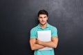 Serious confident young man standing and holding laptop Royalty Free Stock Photo